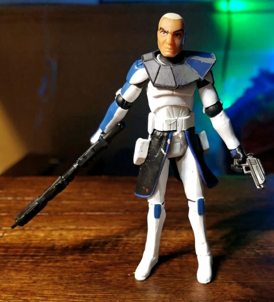 Captain Rex Star Wars action figure in white blue armor holding blasters on wooden surface wallpaper