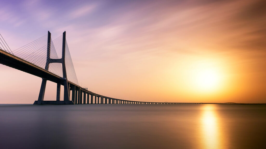Spectacular Sunset at Vasco da Gama Bridge: Magnificent Portuguese Scenery by the Serene Ocean Wallpaper