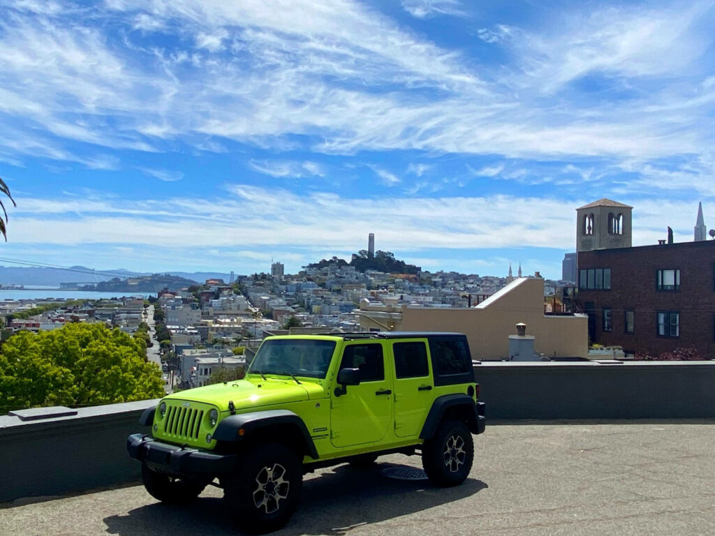 San Francisco's Iconic Coit Tower Captured in a Stunning Shot amidst the Picturesque Russian Hill with a Striking Contrast of a Red Jeep Wallpaper