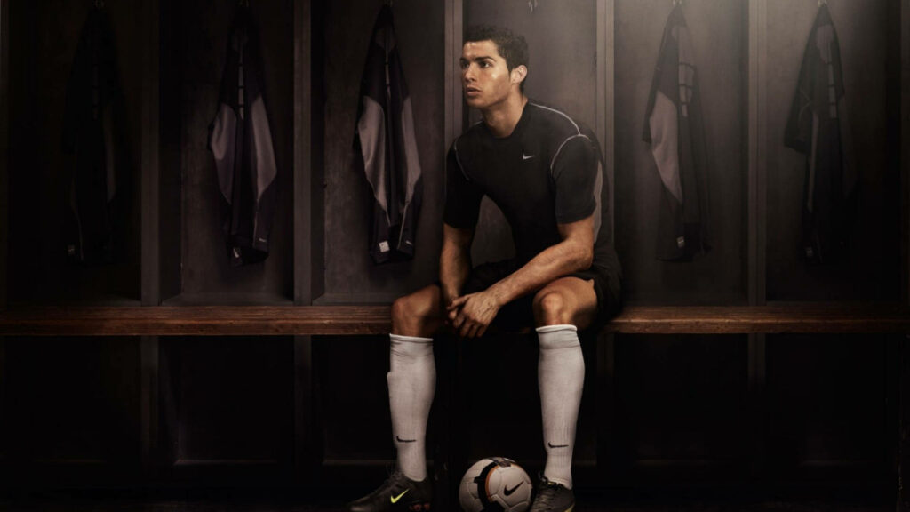 Cristiano Ronaldo seated in dark locker room with soccer ball dramatic HD football wallpaper background