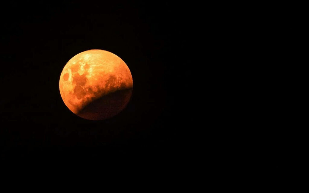 Stunning Lunar Eclipse Wallpaper: Orange Moon Against Dark Space