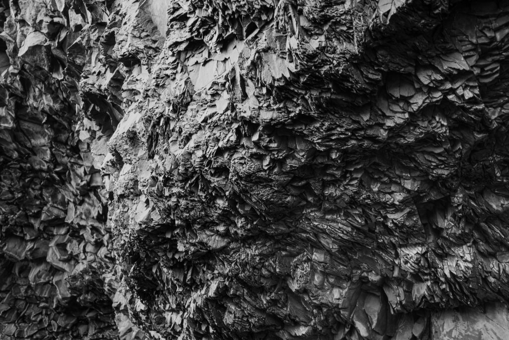 High Resolution Close-Up of a Rough Black Rock with Visible Texture in the Background Wallpaper