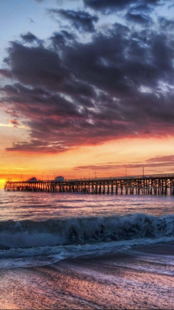 Malibu Beachscape: Serene Sunset Dock amidst Cloudy Skies Wallpaper