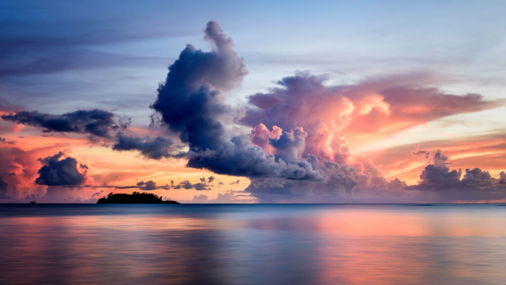 Sunset over calm sea with vibrant orange pink sky clouds and distant island silhouette wallpaper