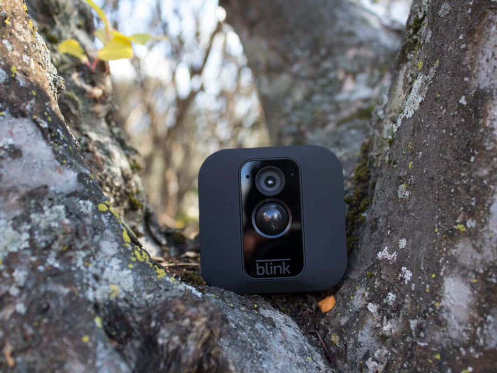 The Ultimate Outdoor Surveillance Solution: Marvel at the Sleek and Discreet Blink XT Security Camera, Masterfully Blending into Any Scenic Background Wallpaper