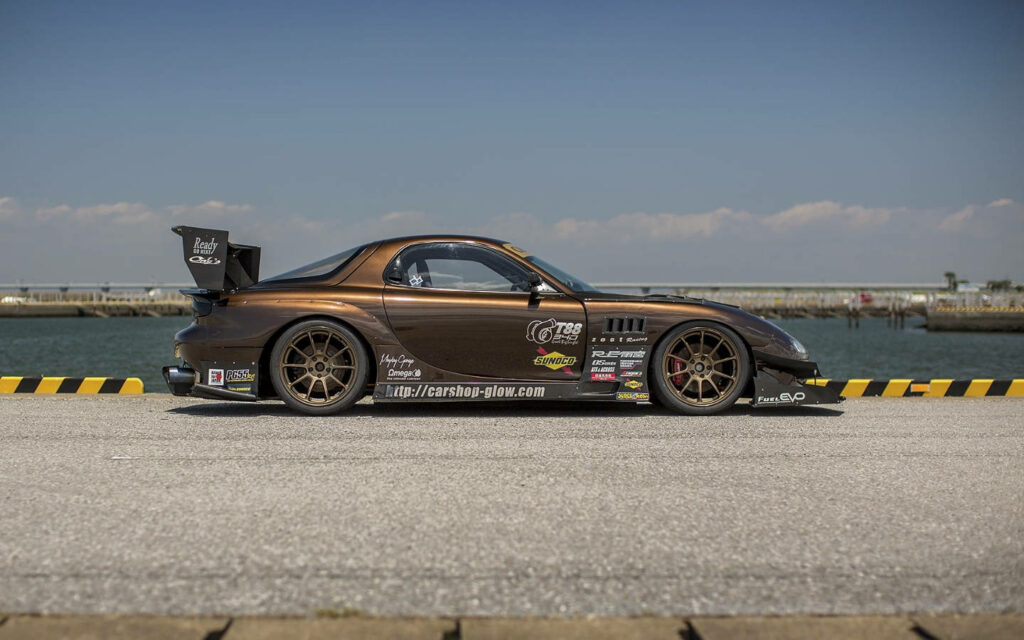 Parked Performance: Captivating Rx-7 showcasing its vibrant decals on a scenic pier Wallpaper