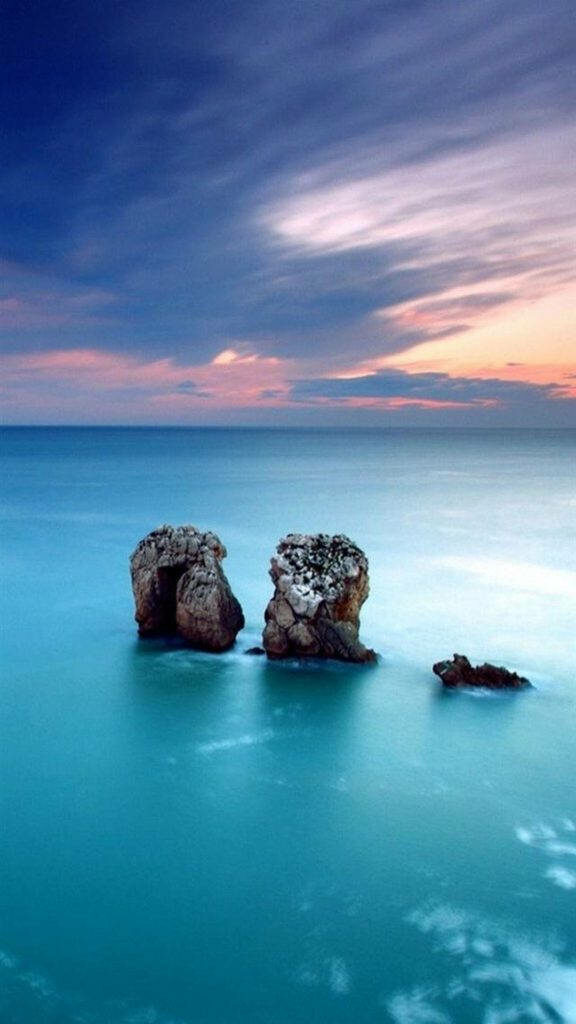 Captivating Sunset Over a Tranquil Blue Water View, framed by Majestic Rock Formations - iPhone X Dynamic Wallpaper