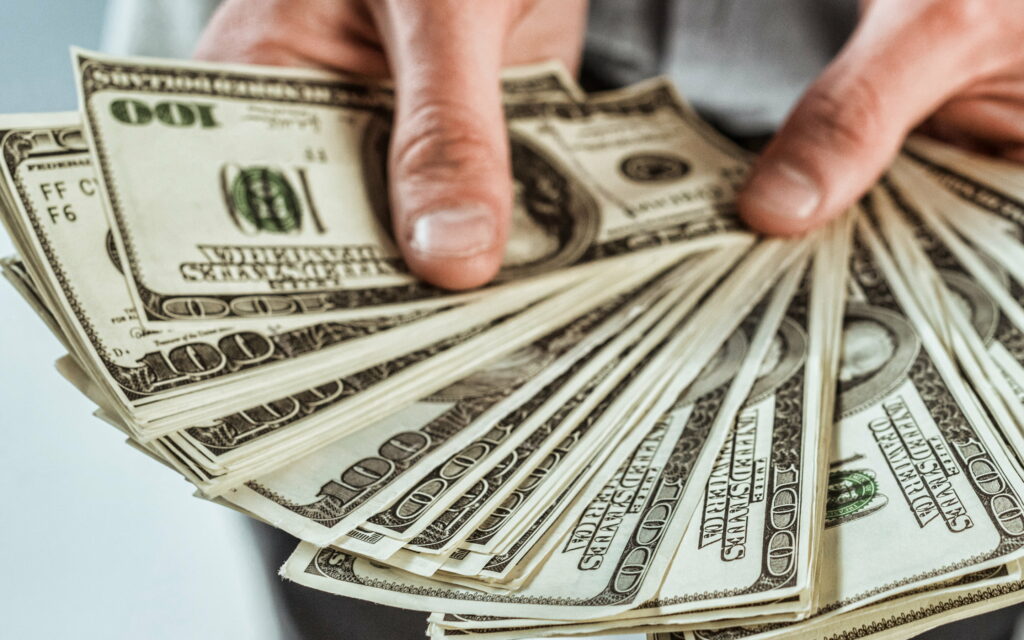 Fortune Filled Fingers: Captivating HD Wallpaper of American Dollars in Hand