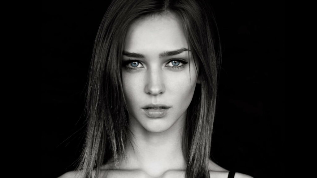 Grayscale portrait of model Rachel Cook with piercing blue eyes on black wallpaper background