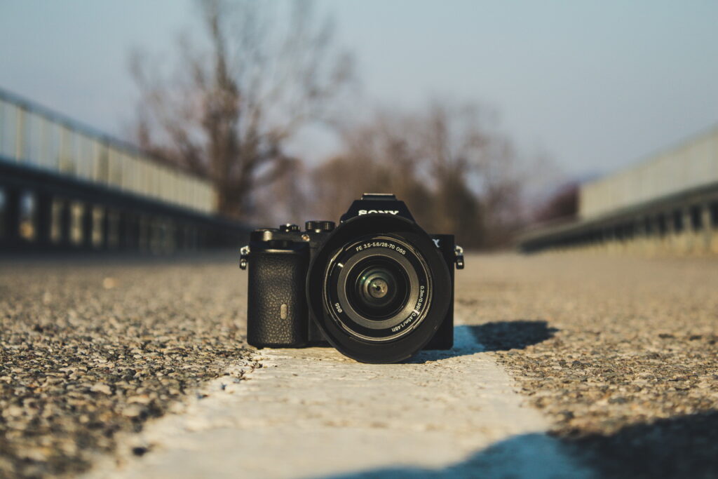 Black Sony mirrorless camera on textured gray concrete with sharp lens and blurred background Wallpaper