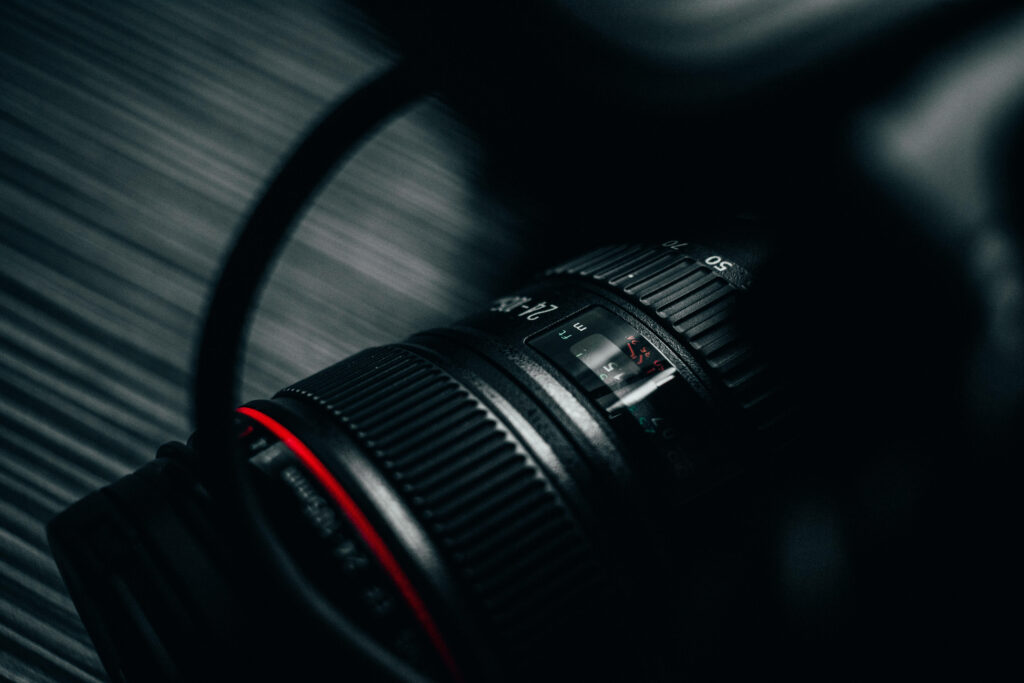Spotlight on a Striking DSLR Camera Lens: Vibrant Red Band Steals the Show in Background Photo Wallpaper