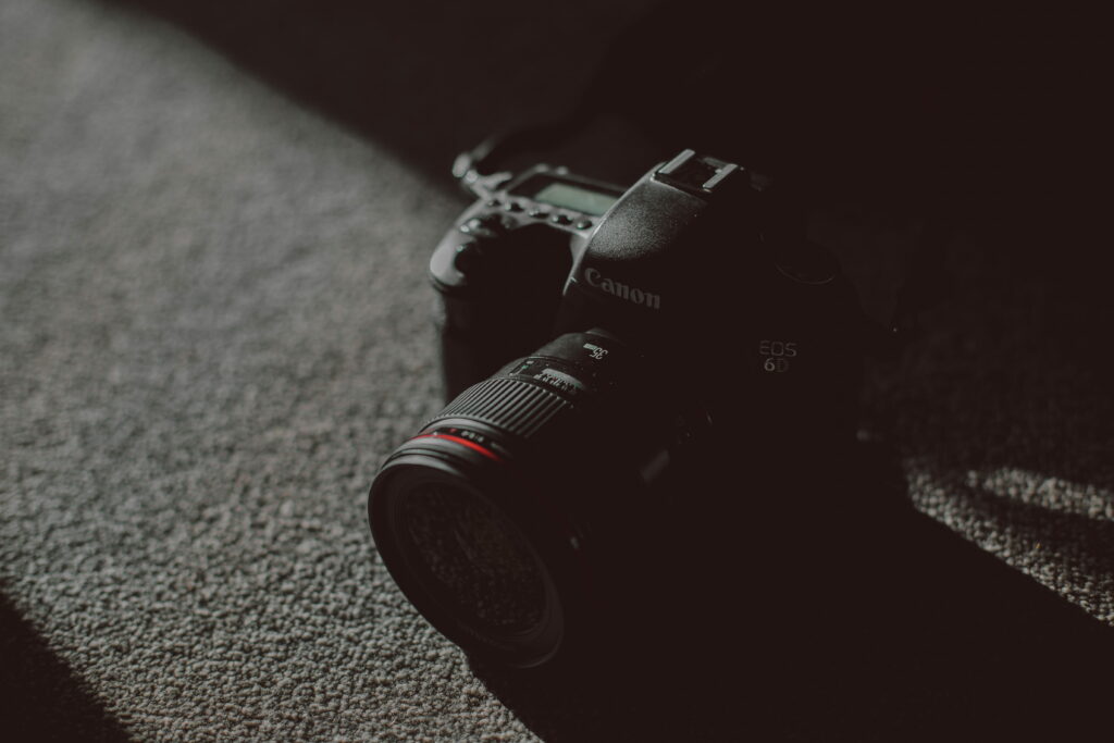 Sleek black Canon EOS 6D DSLR with 35mm lens on gray textile in moody high-contrast light Wallpaper