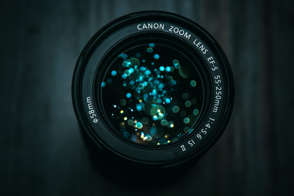 Macro photo of Canon EF-S 55-250mm lens with blue and gold bokeh reflections background Wallpaper
