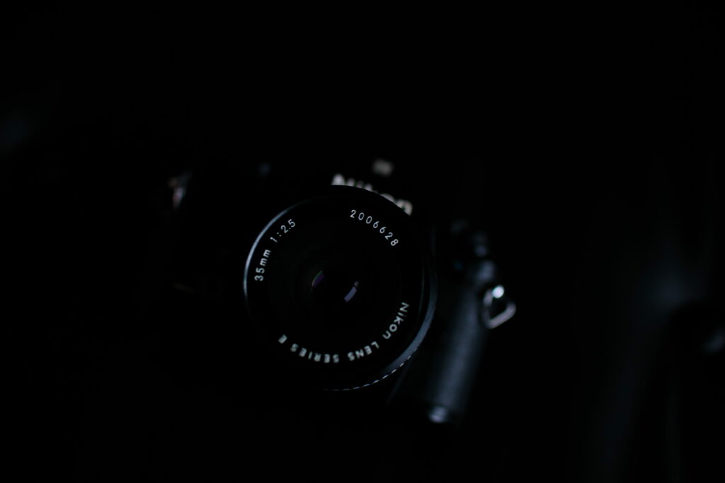 Nikon Series E 35mm f2.5 lens on camera dark moody photography wallpaper background depth of field