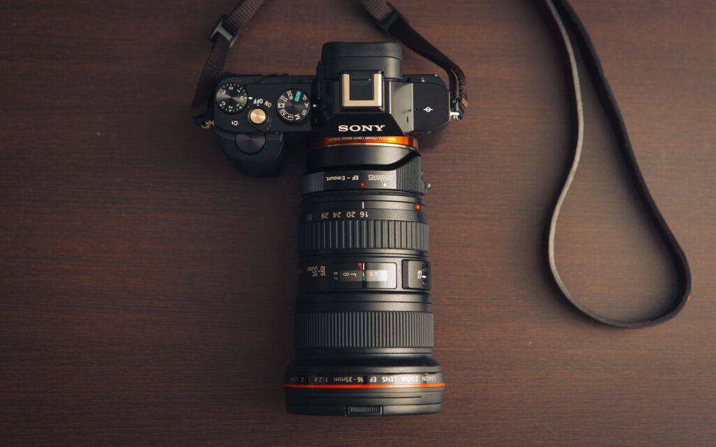 Capturing Technology: Sleek Sony DSLR Camera on Textured Wooden Surface, Perfect for Photography Aficionados, QHD Wallpaper Background