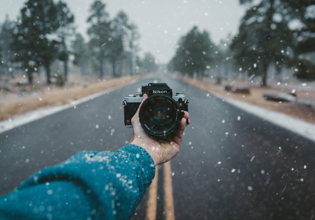 Capturing Memories: A Person Holding a Nikon DSLR Camera Against a Stunning Wallpaper