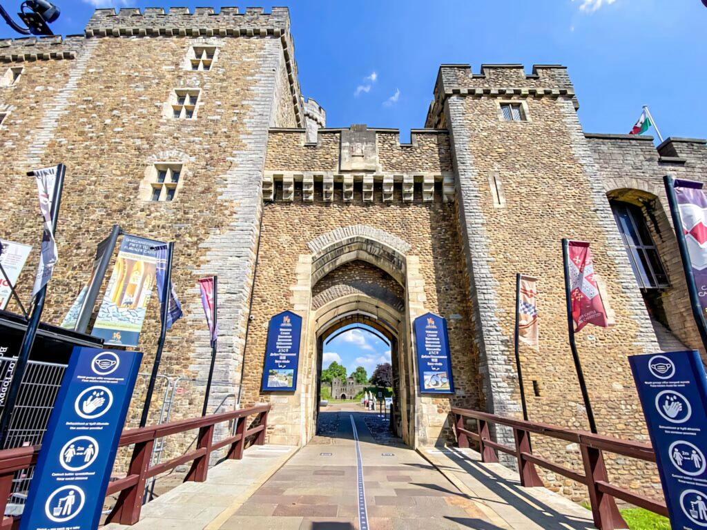 Cardiff Castle main gate stone architecture with flags under clear blue sky daylight wallpaper background