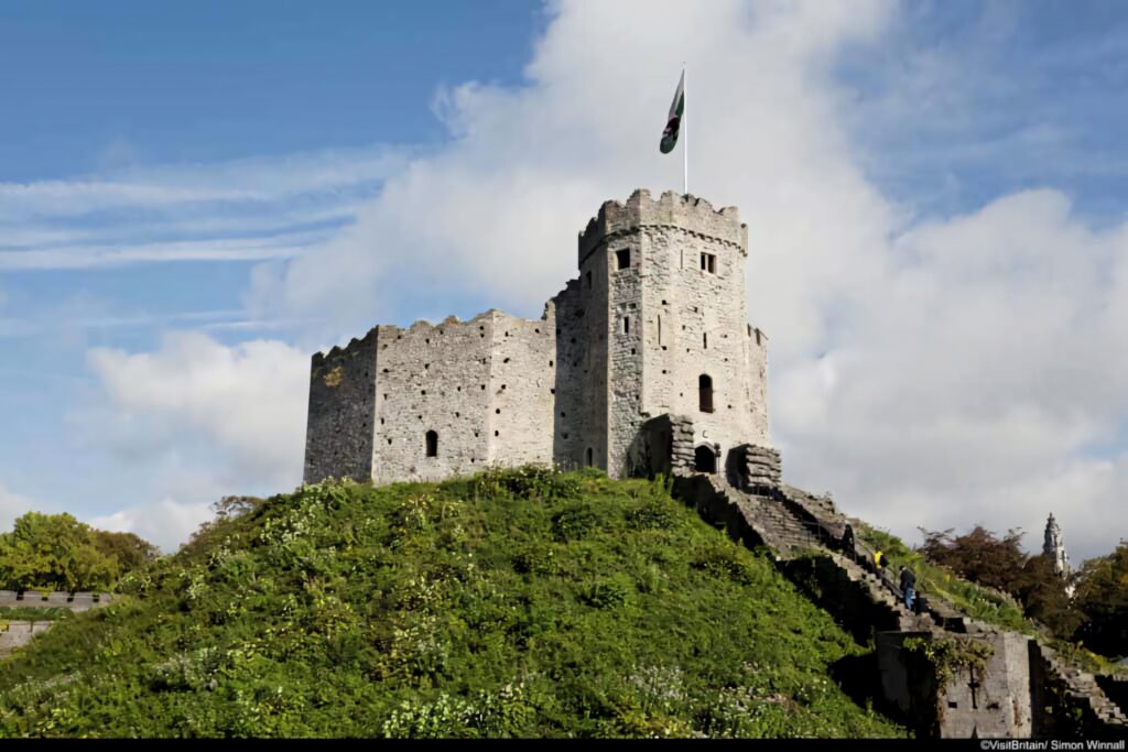 Cardiff Castle side view with historic stone walls medieval architecture and Welsh flag flying Wallpaper