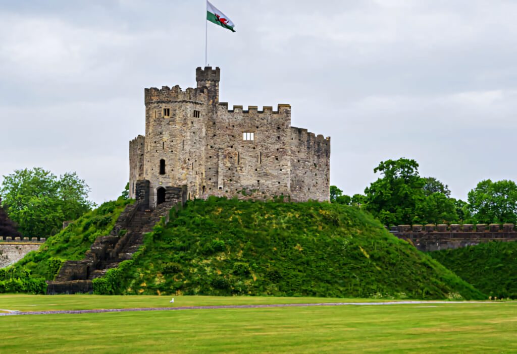 Cardiff Castle stone keep on green motte with manicured lawns under cloudy sky wallpaper