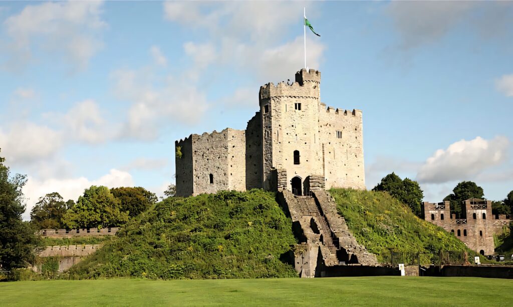 Cardiff Castle stone keep on green hill under blue sky with clouds historic medieval wallpaper