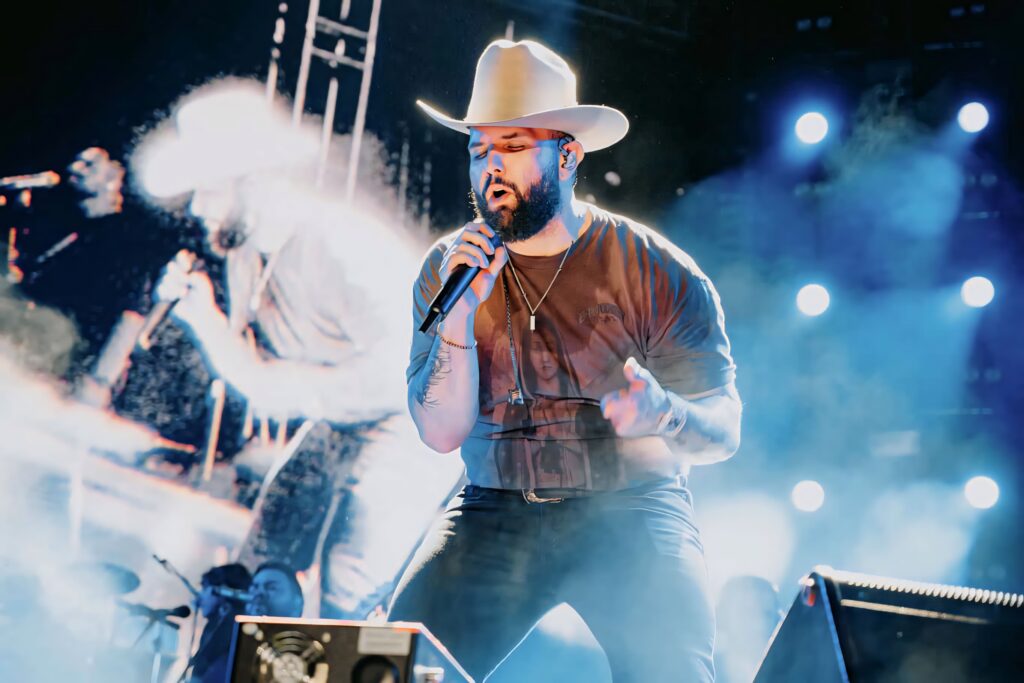 Carin León country music performance live stage blue gold lighting cowboy hat concert effects Wallpaper