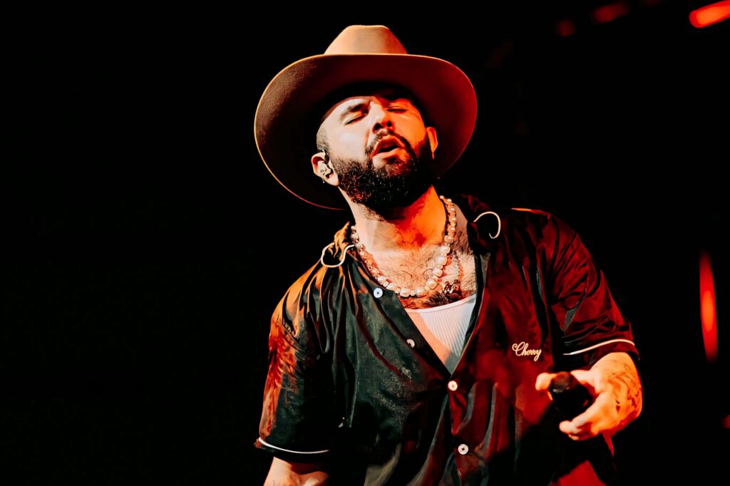 Carin León performing live on stage with dramatic lighting cowboy hat energetic music wallpaper