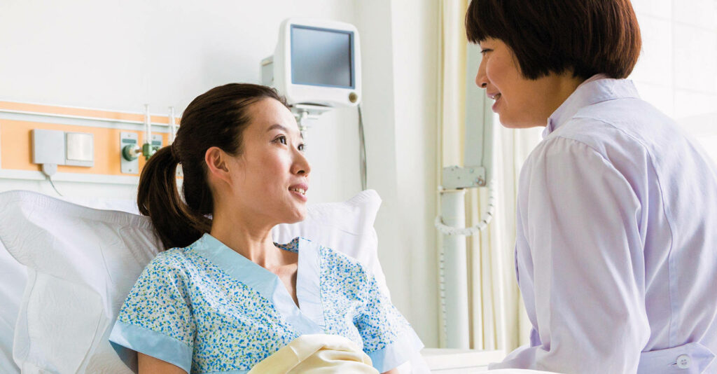 Caring doctor in white coat attentively checking patient in hospital bed with bright medical setting Wallpaper