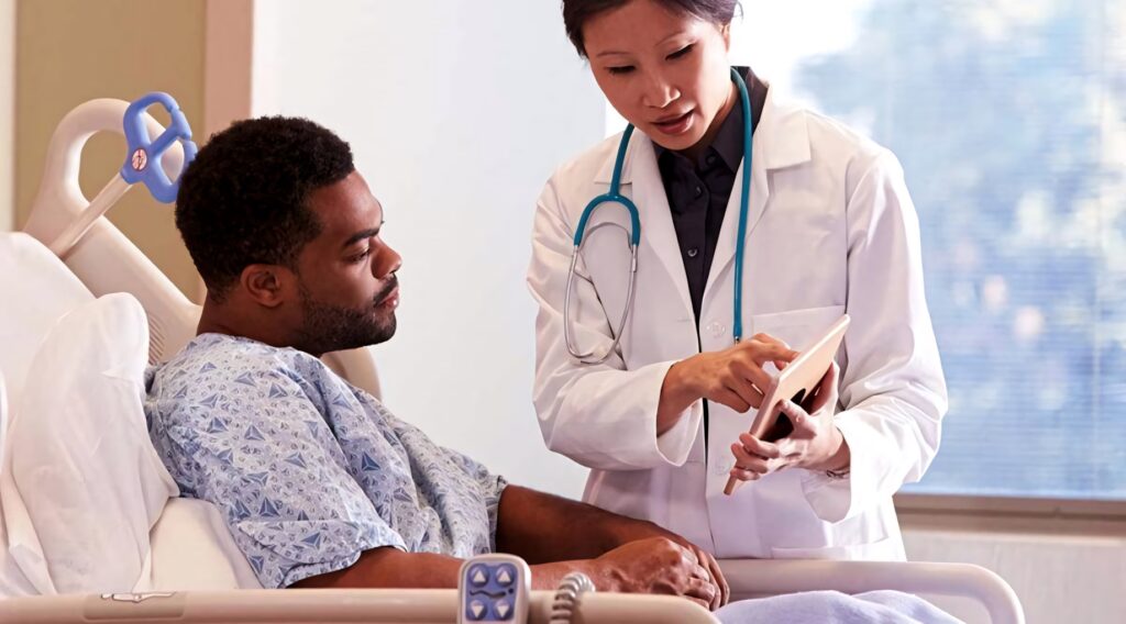 Doctor with stethoscope explains health information on tablet to patient in hospital bed natural light Wallpaper
