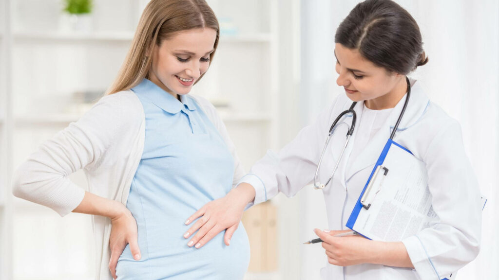 Compassionate female doctor with stethoscope gently examining smiling pregnant woman prenatal care Wallpaper