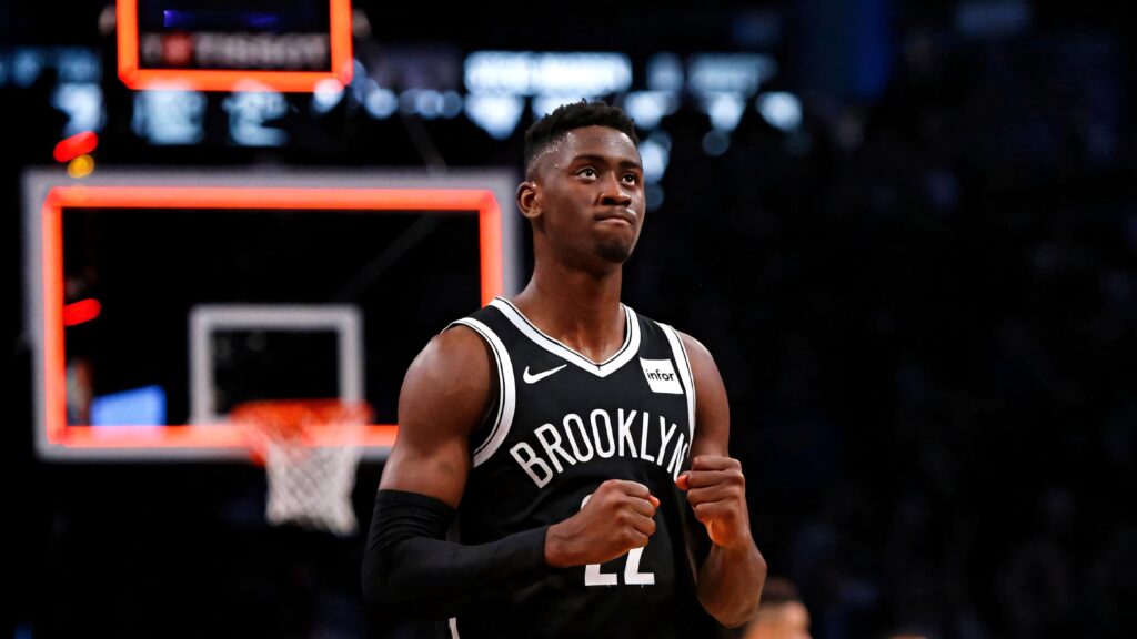 Caris LeVert focused in Brooklyn Nets jersey mid-game dramatic lighting basketball wallpaper background