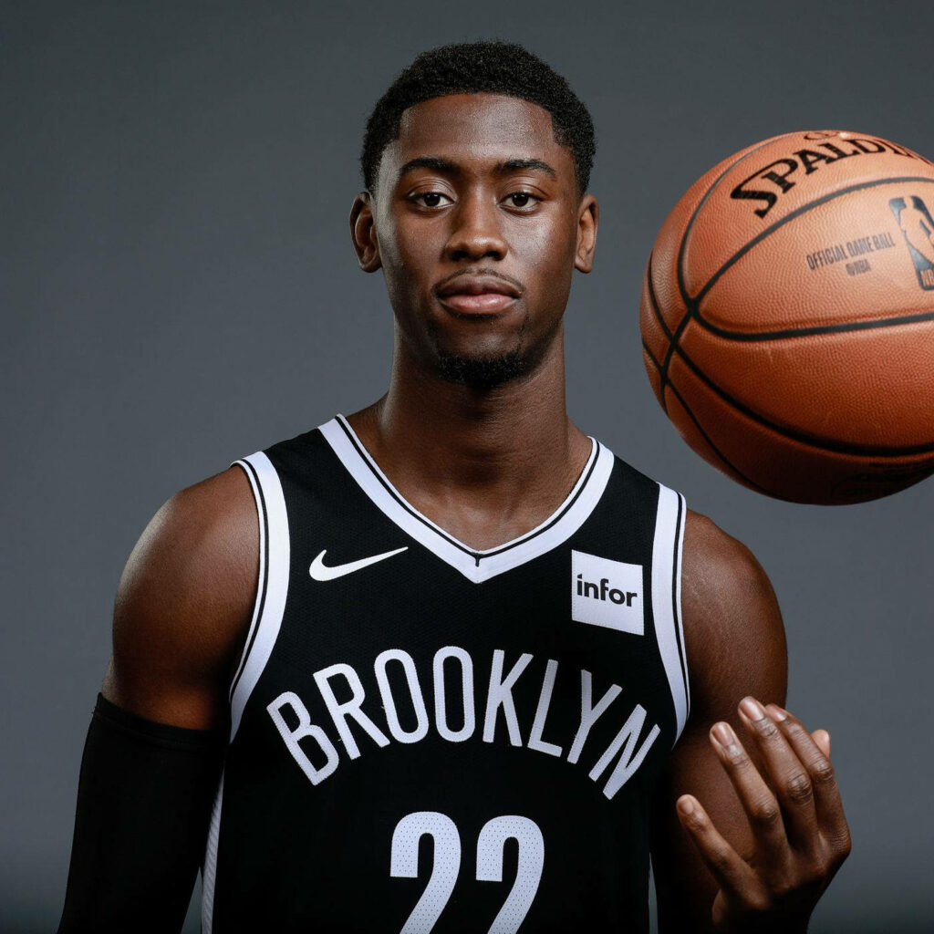 Caris LeVert in Brooklyn Nets jersey holding basketball against gray background modern style Wallpaper