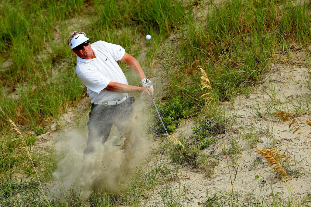 Carl Pettersson golf shot escaping bunker with sand spray and vibrant green course background Wallpaper
