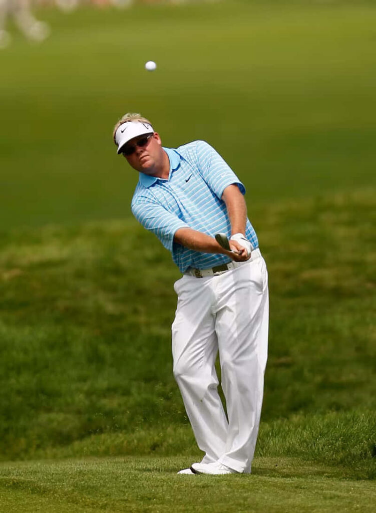 Carl Pettersson mid-swing on green golf course wearing blue striped shirt and white pants Wallpaper