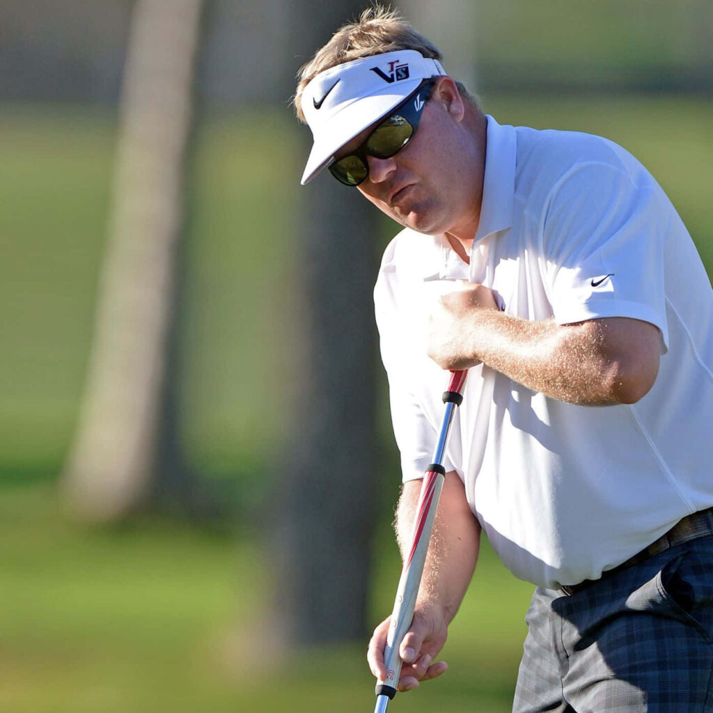 Carl Pettersson mid-swing on sunlit golf course wearing white polo and visor focused stance Wallpaper