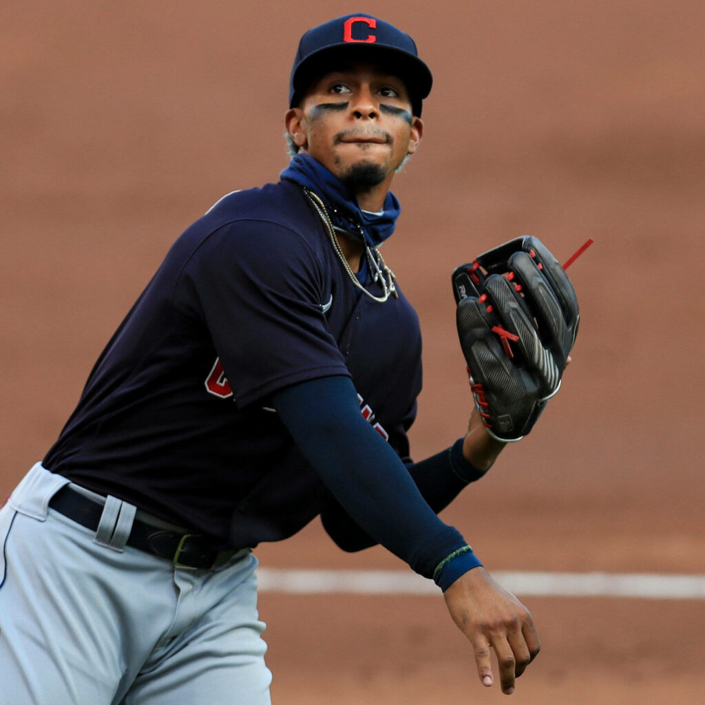 Carlos Carrasco pitching in navy Cleveland baseball uniform with black cheek paint on field background Wallpaper