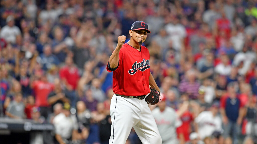 Carlos Carrasco in red Cleveland Indians jersey celebrates triumph on vibrant baseball field crowd background Wallpaper