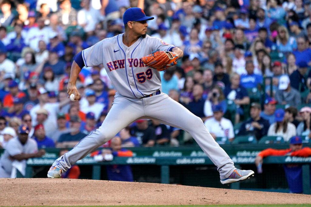 Carlos Carrasco pitching for New York Mets in vibrant stadium crowd high intensity baseball action Wallpaper