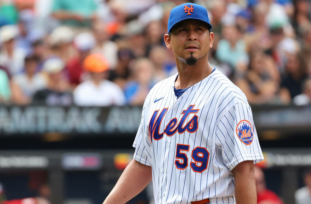 Carlos Carrasco in New York Mets pinstripe jersey number 59 looking up on lively baseball field Wallpaper