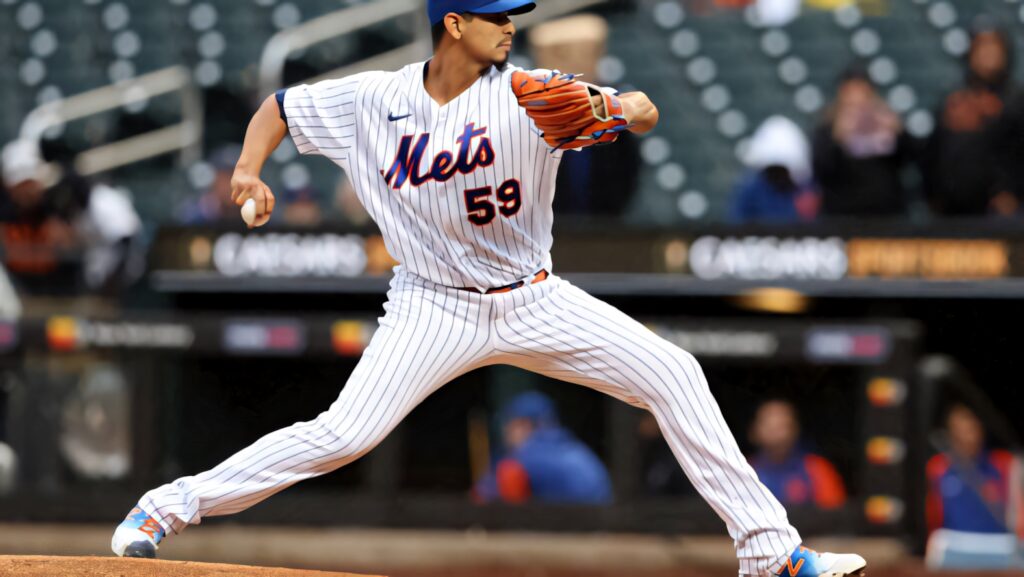 Carlos Carrasco pitching for New York Mets in dynamic stadium shot with vibrant pinstripes background Wallpaper