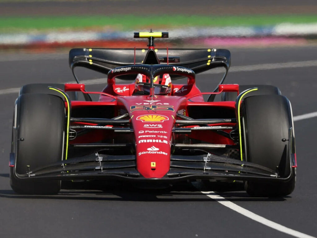 Carlos Sainz Jr. racing Ferrari Formula 1 car at high speed on racetrack dynamic motorsport wallpaper