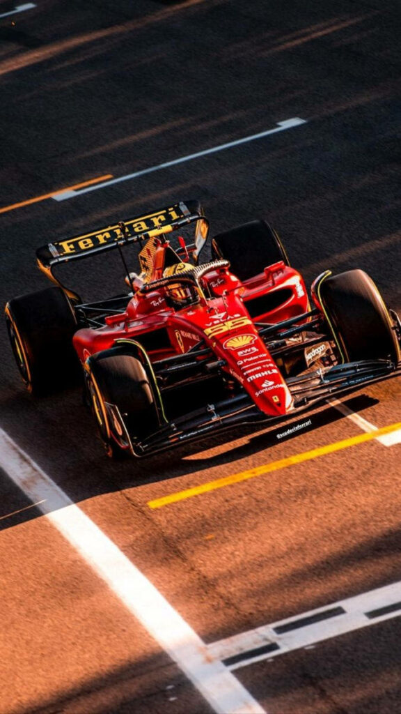 Carlos Sainz Jr. driving Ferrari F1 car at golden hour showcasing speed and intensity wallpaper