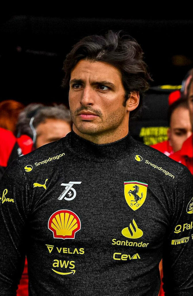 Carlos Sainz Jr in black Ferrari racing suit with prancing horse emblem ready for F1 race day Wallpaper