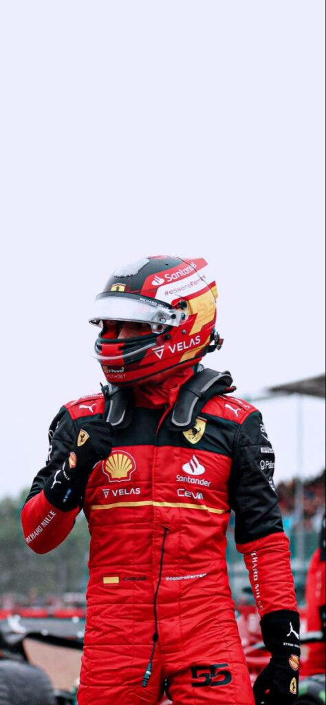 Carlos Sainz Jr in red Ferrari racing suit and helmet showcasing speed and determination wallpaper