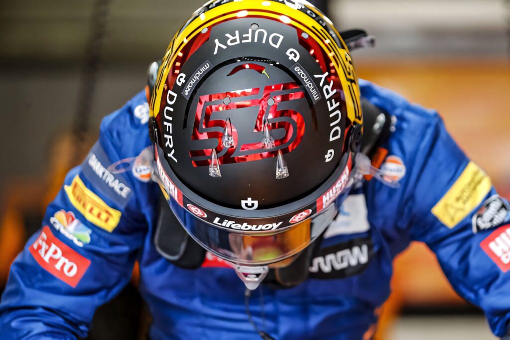 Carlos Sainz Jr in vibrant blue suit and red yellow helmet with number 55 racing in Formula 1 Wallpaper