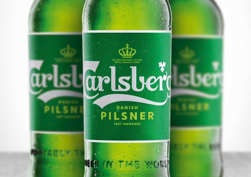 Close-up of cold Carlsberg Pilsner green bottle with condensation on vibrant background wallpaper