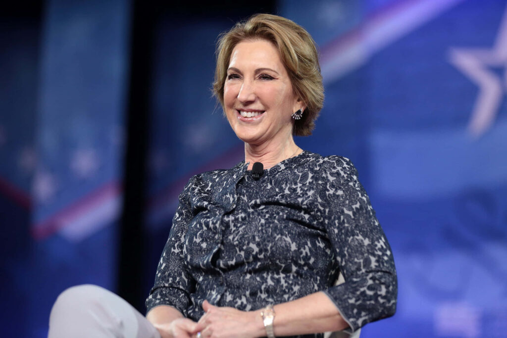 Carly Fiorina relaxing on stage at RNC in patterned blouse with American flag blue lit background Wallpaper
