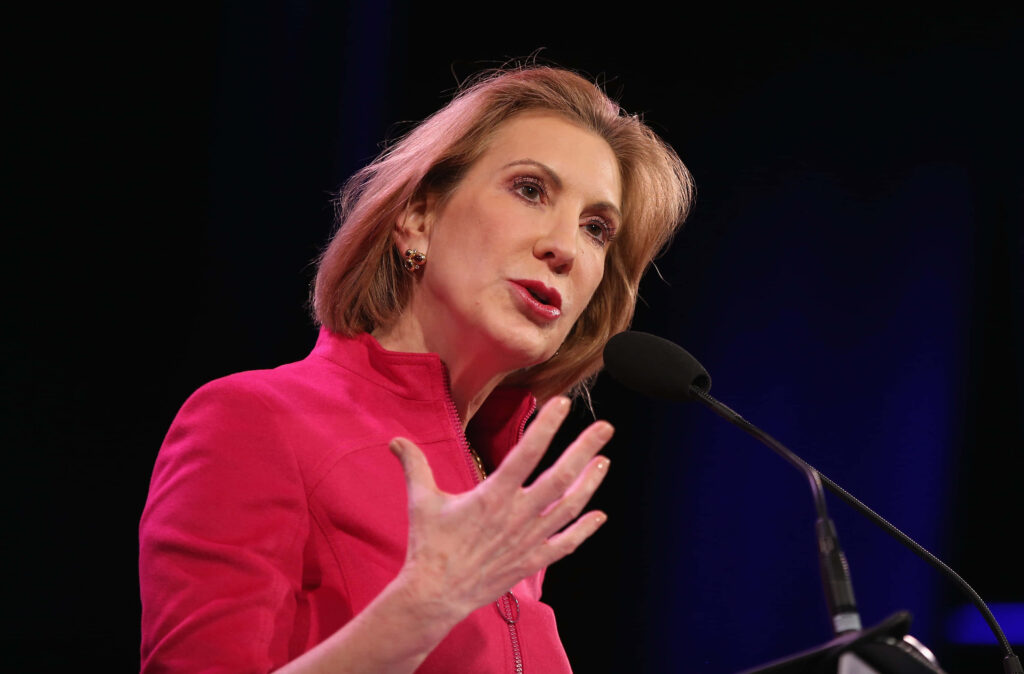 Carly Fiorina speaking at podium wearing bright pink jacket confident leadership wallpaper background