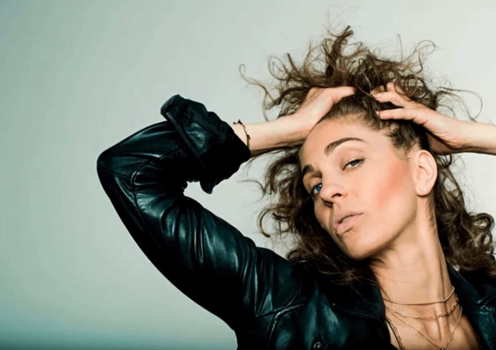 Carmel Amit confident portrait curly hair black leather jacket expressive gaze dramatic lighting Wallpaper