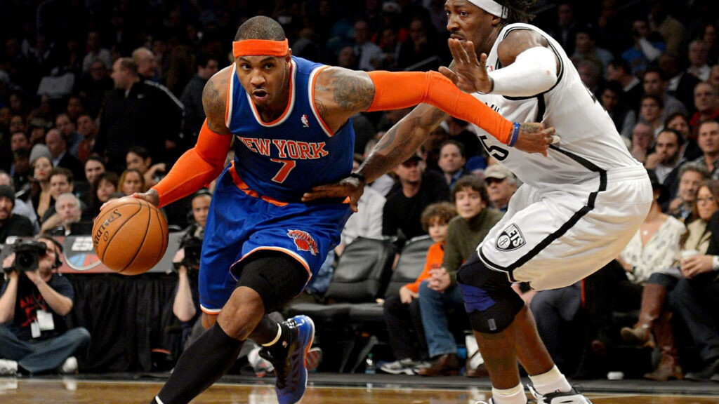 Carmelo Anthony driving past Brooklyn Nets defender in blue orange Knicks uniform NBA action Wallpaper