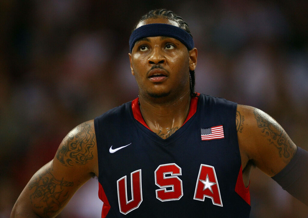 Carmelo Anthony focused in navy USA Basketball jersey intense Olympic game action under stadium lights Wallpaper
